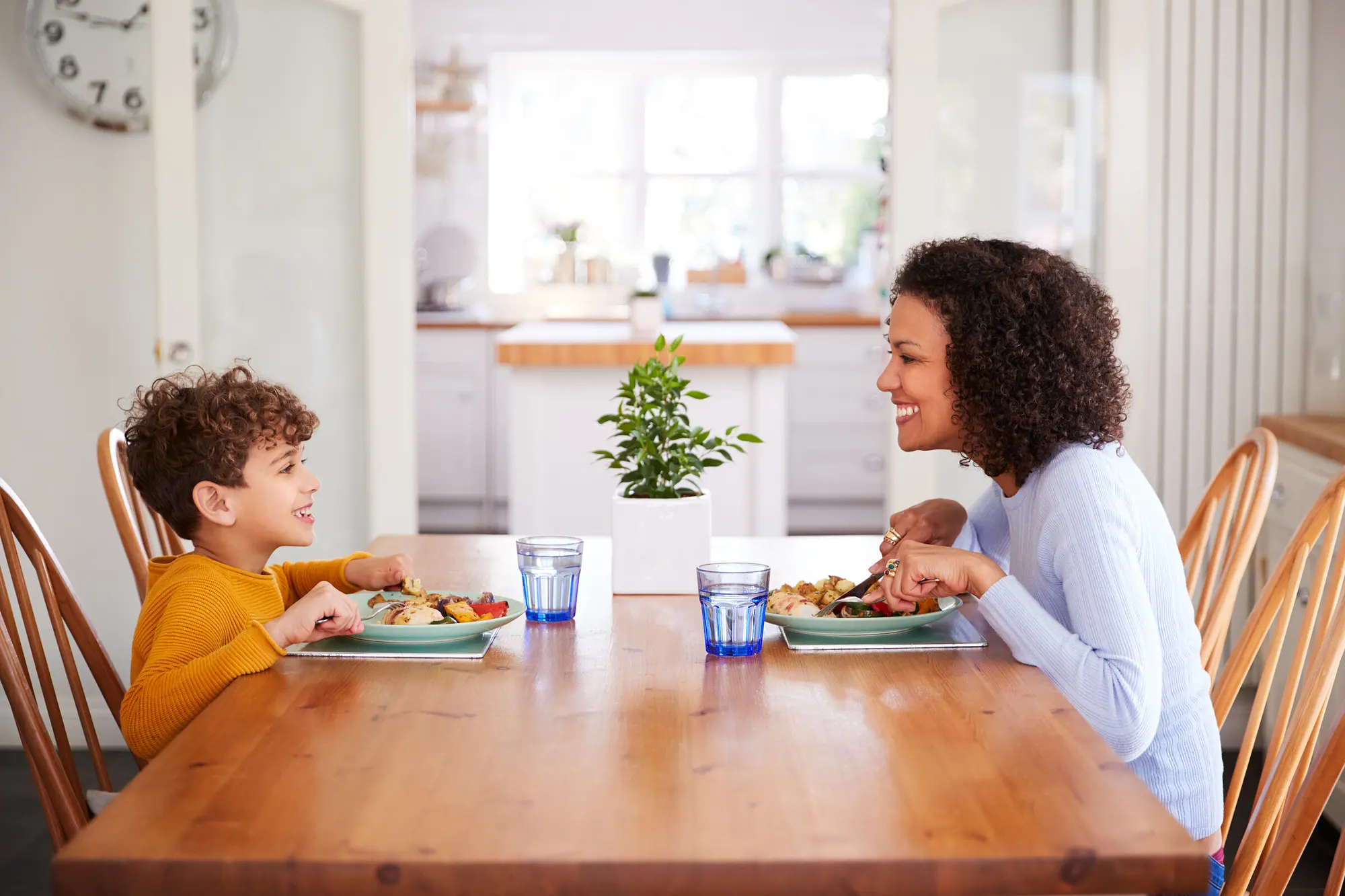 Wide shot — a parent and kids at the table, house handled